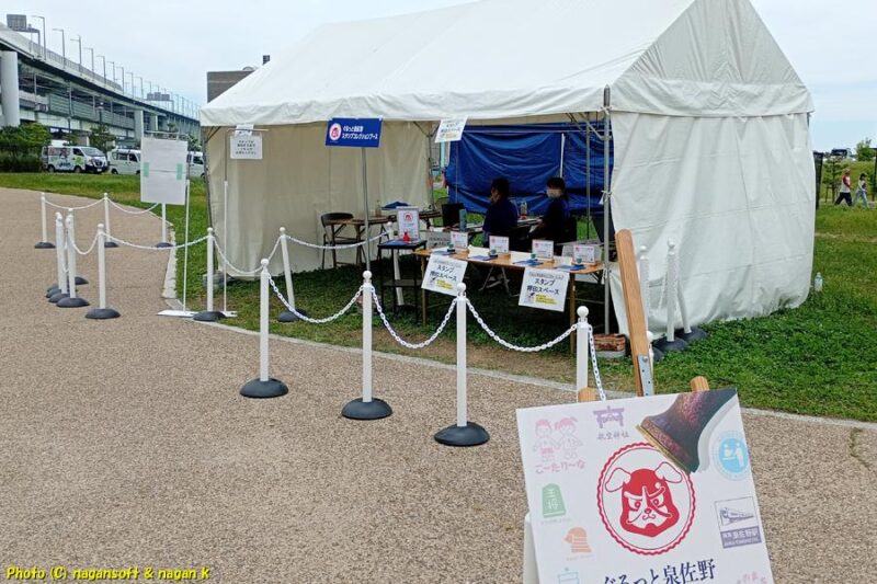 「いずみさのカレーサミット2026」イベント会場内に設置された「ぐるっと泉佐野スタンプコレクション」スタンプ会場。テントが設置されスタッフが待機している。スタッフの前に複数のスタンプが置かれている｜大阪府泉佐野市｜2026年05月31日撮影