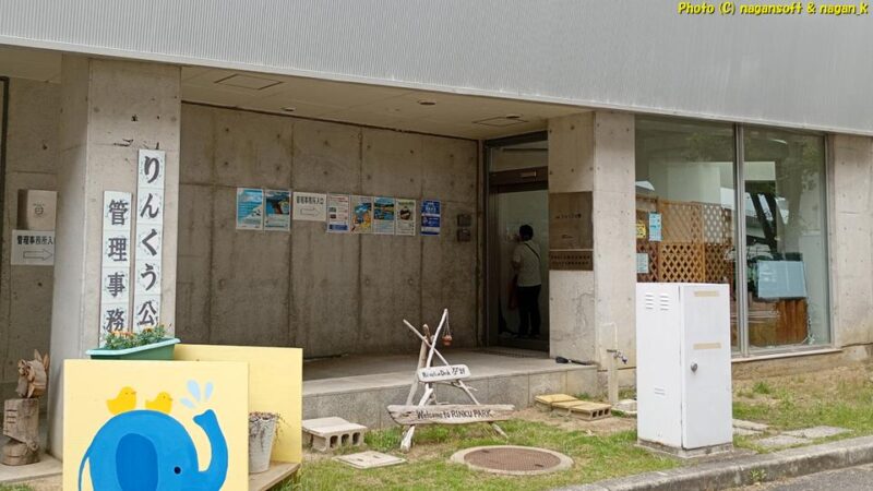 “りんくう公園管理事務所”の入り口から、さらに建物の反対側へ回れと指示され、たどり着いた一般客用と思われる玄関。建屋に各種ポスターが貼られている｜大阪府泉佐野市｜2026年05月31日撮影