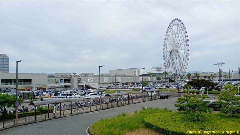 りんくう公園「海への橋」を“りんくうシークル”側へ渡り、“りんくうシークル”を見渡した景色。ショッピングモールと観覧車、手前に駐車場｜泉佐野市｜2026年05月31日撮影